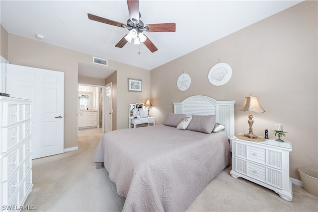 bedroom featuring ensuite bathroom, light colored carpet, and ceiling fan