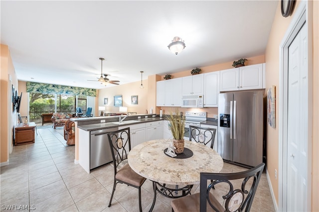 kitchen featuring light tile flooring, ceiling fan, stainless steel appliances, kitchen peninsula, and white cabinetry