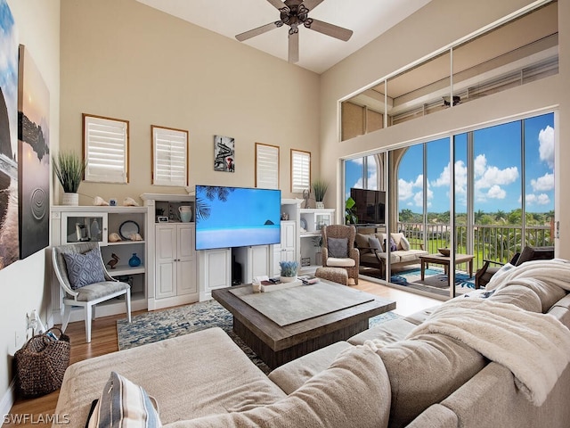 living room with a high ceiling, ceiling fan, and hardwood / wood-style flooring