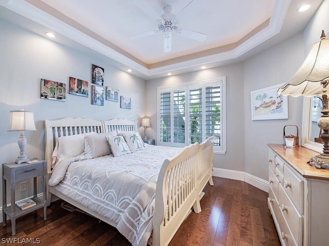 bedroom with ceiling fan, dark wood-type flooring, and a tray ceiling