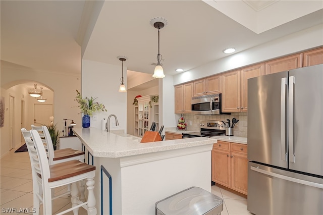 kitchen with decorative light fixtures, appliances with stainless steel finishes, light brown cabinets, light tile floors, and tasteful backsplash