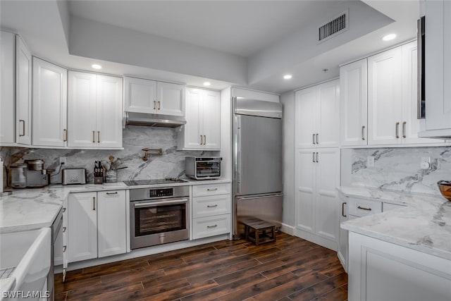 kitchen with dark hardwood / wood-style flooring, light stone countertops, backsplash, and stainless steel appliances