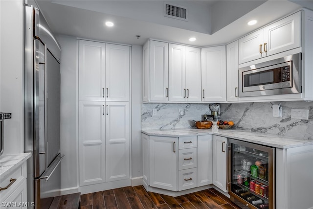 kitchen featuring light stone countertops, dark hardwood / wood-style flooring, appliances with stainless steel finishes, and wine cooler