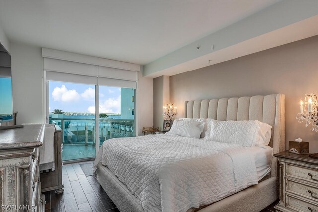 bedroom featuring access to exterior, hardwood / wood-style floors, and an inviting chandelier