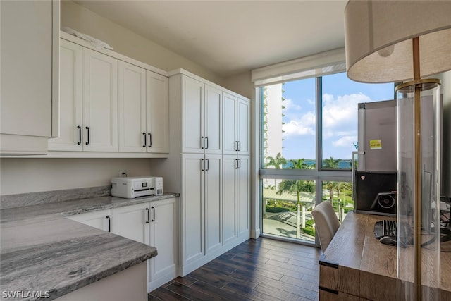 kitchen featuring dark wood-type flooring, white cabinetry, and light stone counters