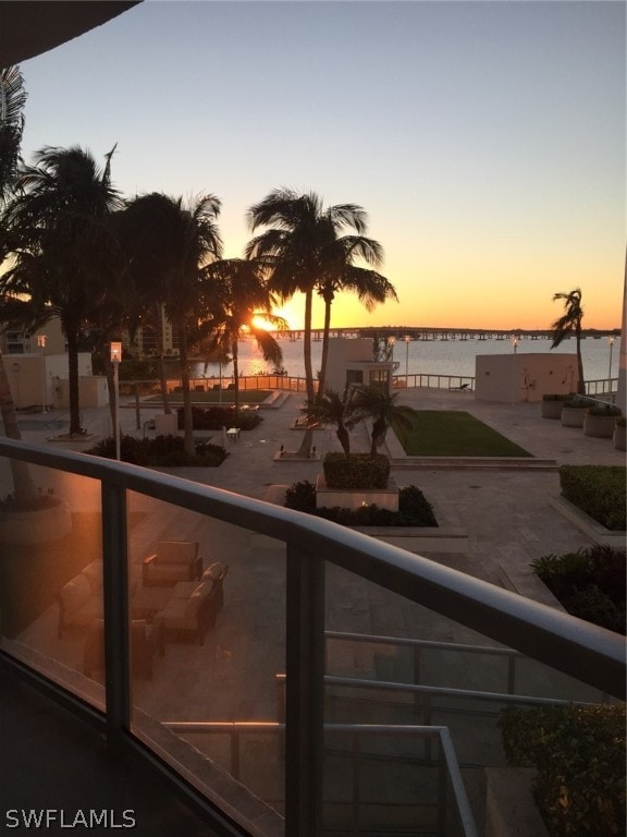 balcony at dusk featuring a water view