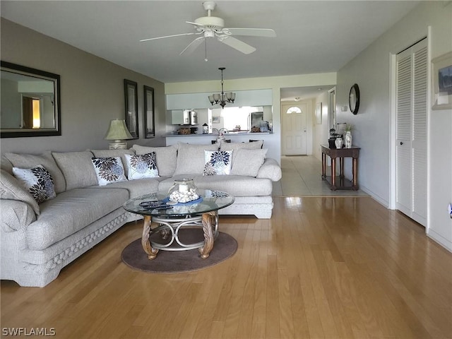 living room with light hardwood / wood-style floors and ceiling fan with notable chandelier