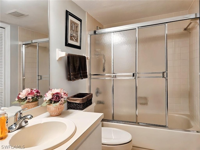 full bathroom featuring bath / shower combo with glass door, toilet, and vanity