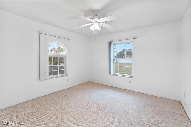 carpeted spare room with a wealth of natural light and ceiling fan