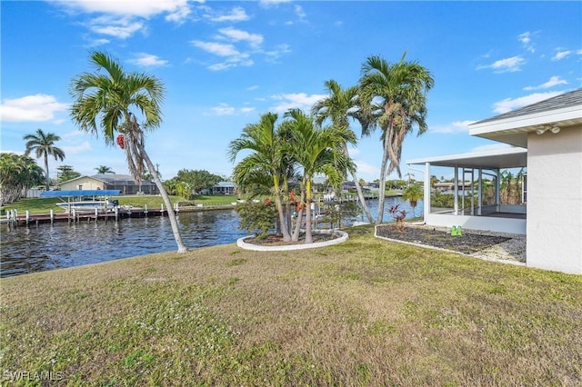 view of yard featuring a sunroom and a water view