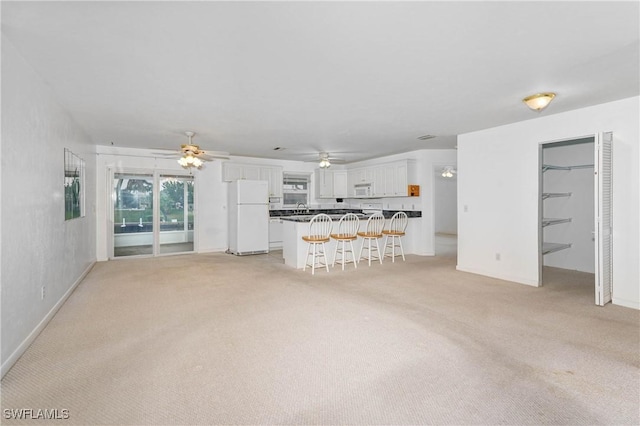 unfurnished living room with ceiling fan and light carpet