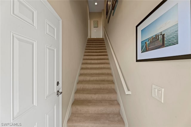 staircase featuring light colored carpet