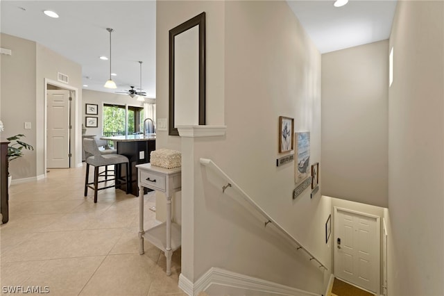 staircase featuring sink, ceiling fan, and light tile flooring