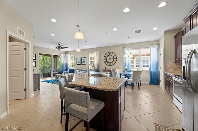 kitchen featuring decorative light fixtures, a kitchen breakfast bar, ceiling fan, and sink