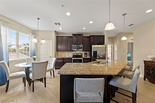 kitchen with decorative light fixtures, tasteful backsplash, sink, and stainless steel appliances