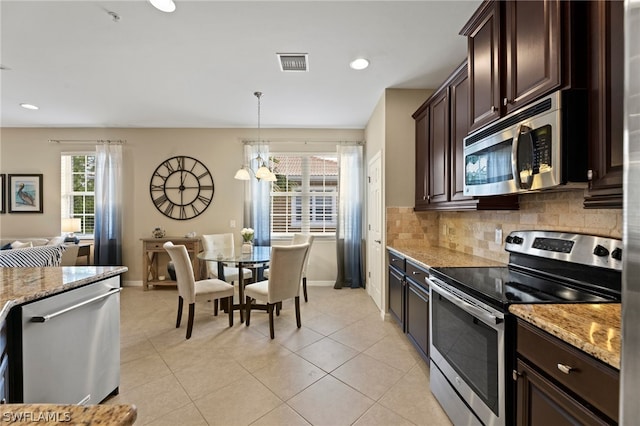 kitchen with tasteful backsplash, stainless steel appliances, pendant lighting, and light stone counters