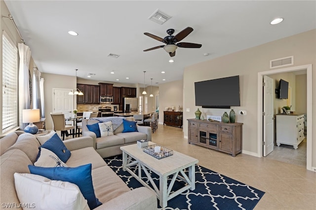 tiled living room with ceiling fan with notable chandelier and a healthy amount of sunlight