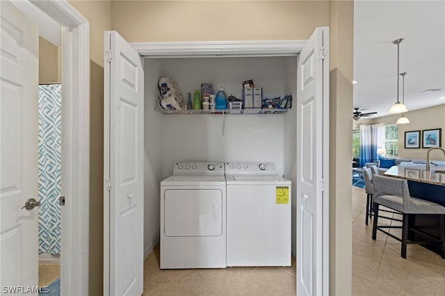 clothes washing area with washer and clothes dryer, ceiling fan, light tile floors, and sink