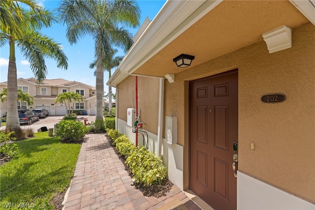 property entrance featuring a lawn and a garage