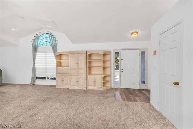 foyer entrance featuring carpet, plenty of natural light, and vaulted ceiling