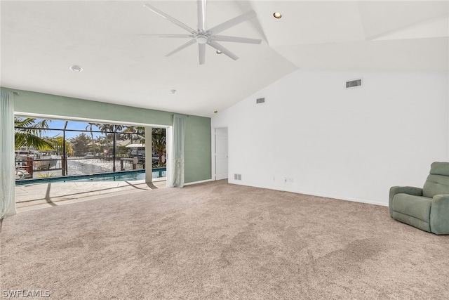 unfurnished living room featuring high vaulted ceiling, a water view, carpet floors, and ceiling fan