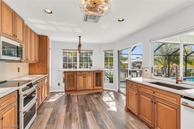 kitchen with white appliances, hardwood / wood-style floors, hanging light fixtures, and sink