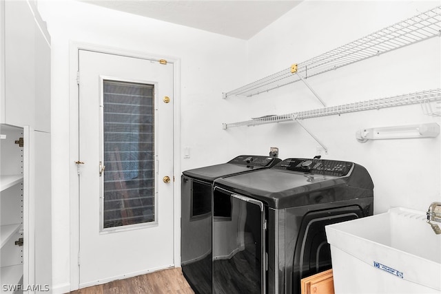 laundry room featuring hardwood / wood-style floors, washer and dryer, and sink