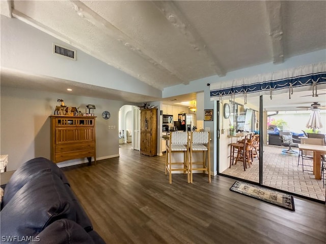 living room with a textured ceiling, vaulted ceiling with beams, and dark hardwood / wood-style floors