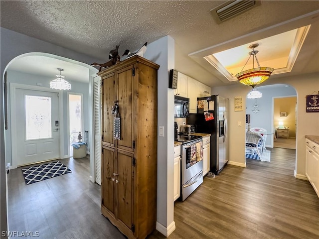 kitchen featuring a tray ceiling, dark hardwood / wood-style flooring, pendant lighting, and appliances with stainless steel finishes