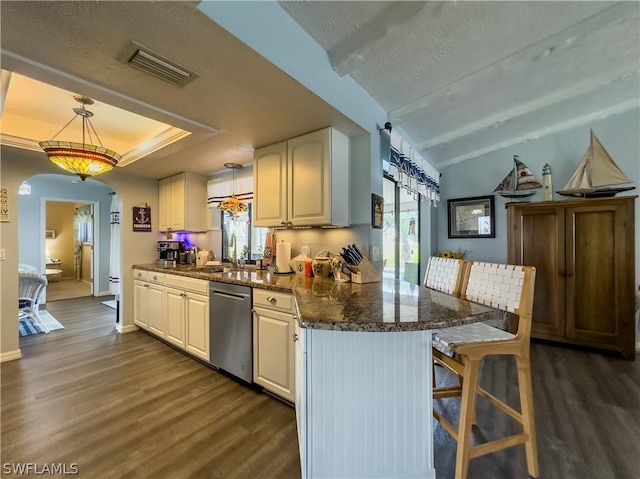 kitchen featuring lofted ceiling, a kitchen breakfast bar, hanging light fixtures, stainless steel dishwasher, and dark hardwood / wood-style floors