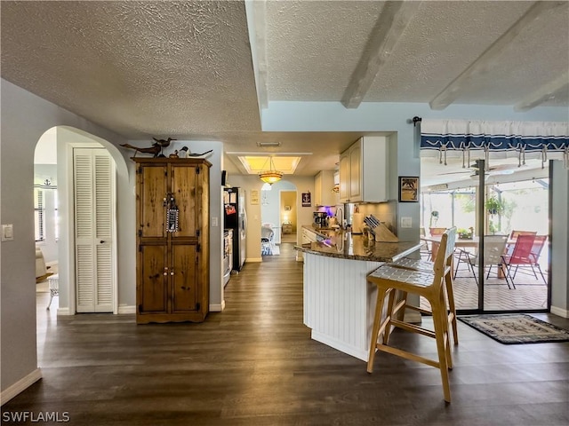 kitchen featuring white cabinets, sink, dark hardwood / wood-style floors, kitchen peninsula, and a breakfast bar area