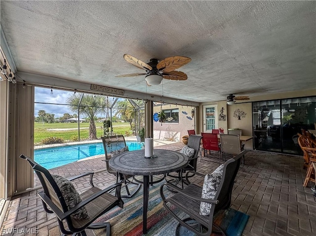 view of patio with glass enclosure and ceiling fan