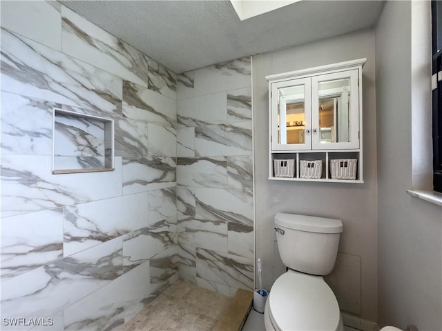 bathroom with toilet, a textured ceiling, and tiled shower