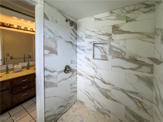 bathroom featuring vanity, a tile shower, and a textured ceiling