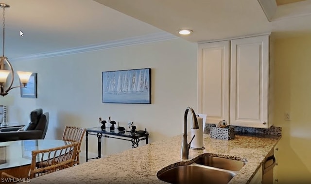 kitchen featuring light stone countertops, white cabinetry, decorative light fixtures, a notable chandelier, and sink