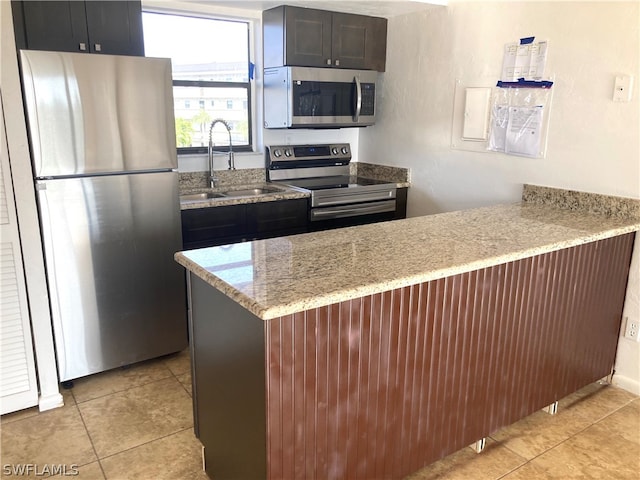 kitchen featuring stainless steel appliances, light tile flooring, sink, and light stone countertops