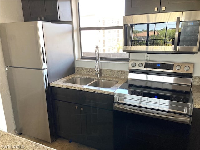 kitchen featuring light stone countertops, appliances with stainless steel finishes, and sink