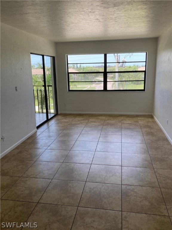 spare room featuring a textured ceiling and light tile floors