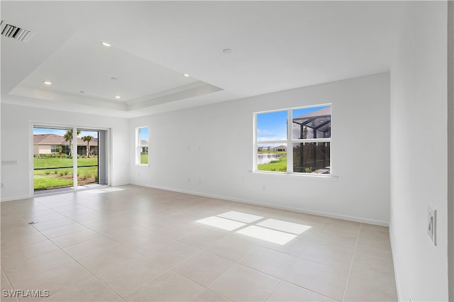 unfurnished room with a raised ceiling and light tile patterned flooring