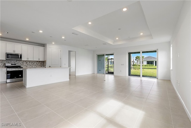 unfurnished living room featuring light tile patterned floors and a tray ceiling