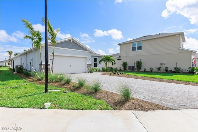 view of front of house featuring cooling unit, a front yard, and a garage