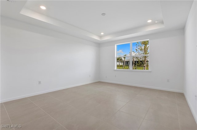 spare room with a raised ceiling and light tile patterned floors