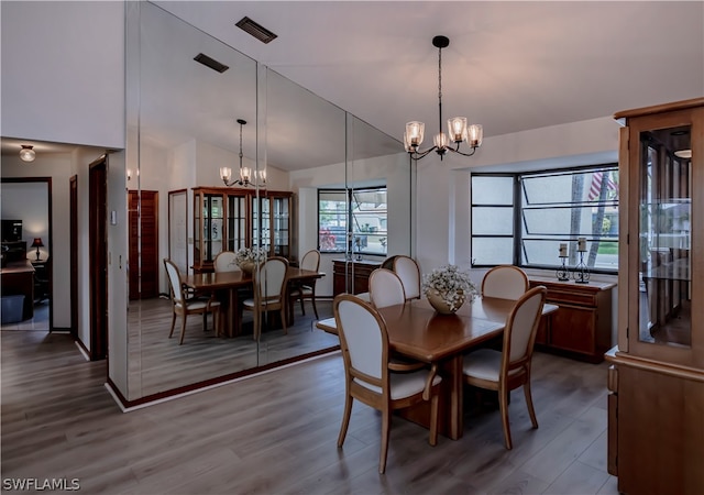 dining area featuring a notable chandelier, lofted ceiling, and wood-type flooring