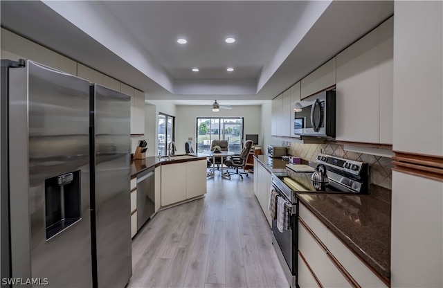 kitchen featuring ceiling fan, white cabinets, light hardwood / wood-style flooring, stainless steel appliances, and a tray ceiling