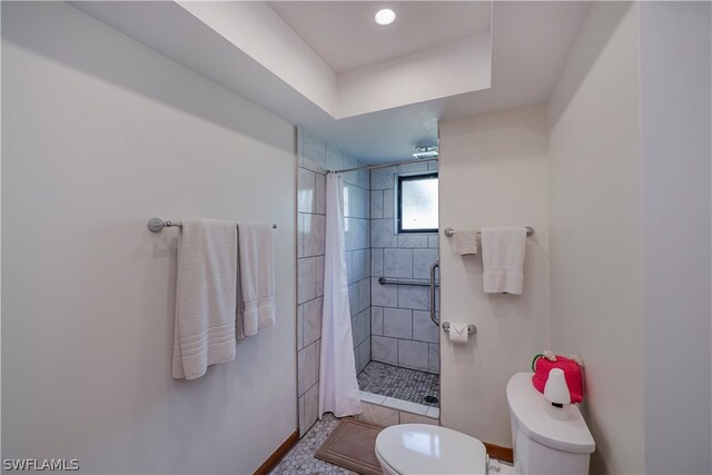 bathroom with toilet, tile floors, and a tile shower