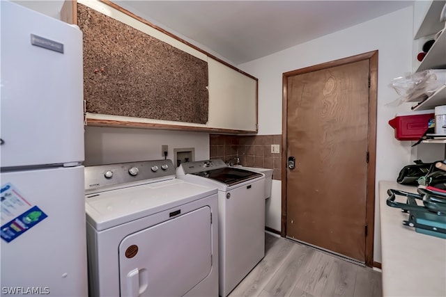 laundry room with washer hookup, independent washer and dryer, sink, and light hardwood / wood-style flooring