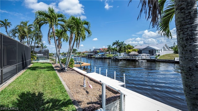 dock area featuring a water view, a lanai, and a yard