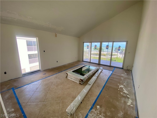 unfurnished living room with high vaulted ceiling and a healthy amount of sunlight