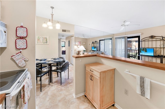 kitchen featuring light brown cabinetry, light tile floors, electric range, decorative light fixtures, and ceiling fan with notable chandelier