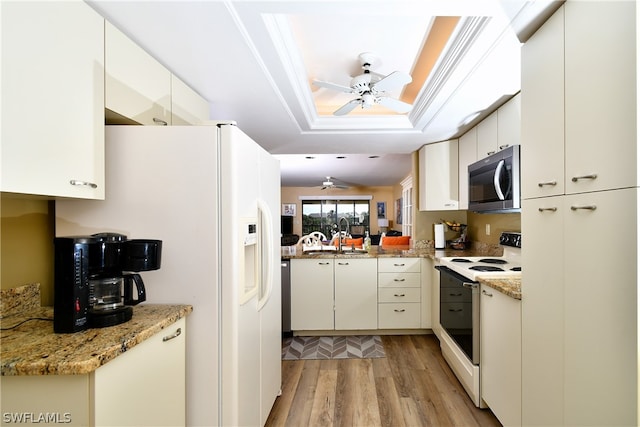 kitchen with white appliances, ceiling fan, light stone counters, light hardwood / wood-style floors, and a tray ceiling